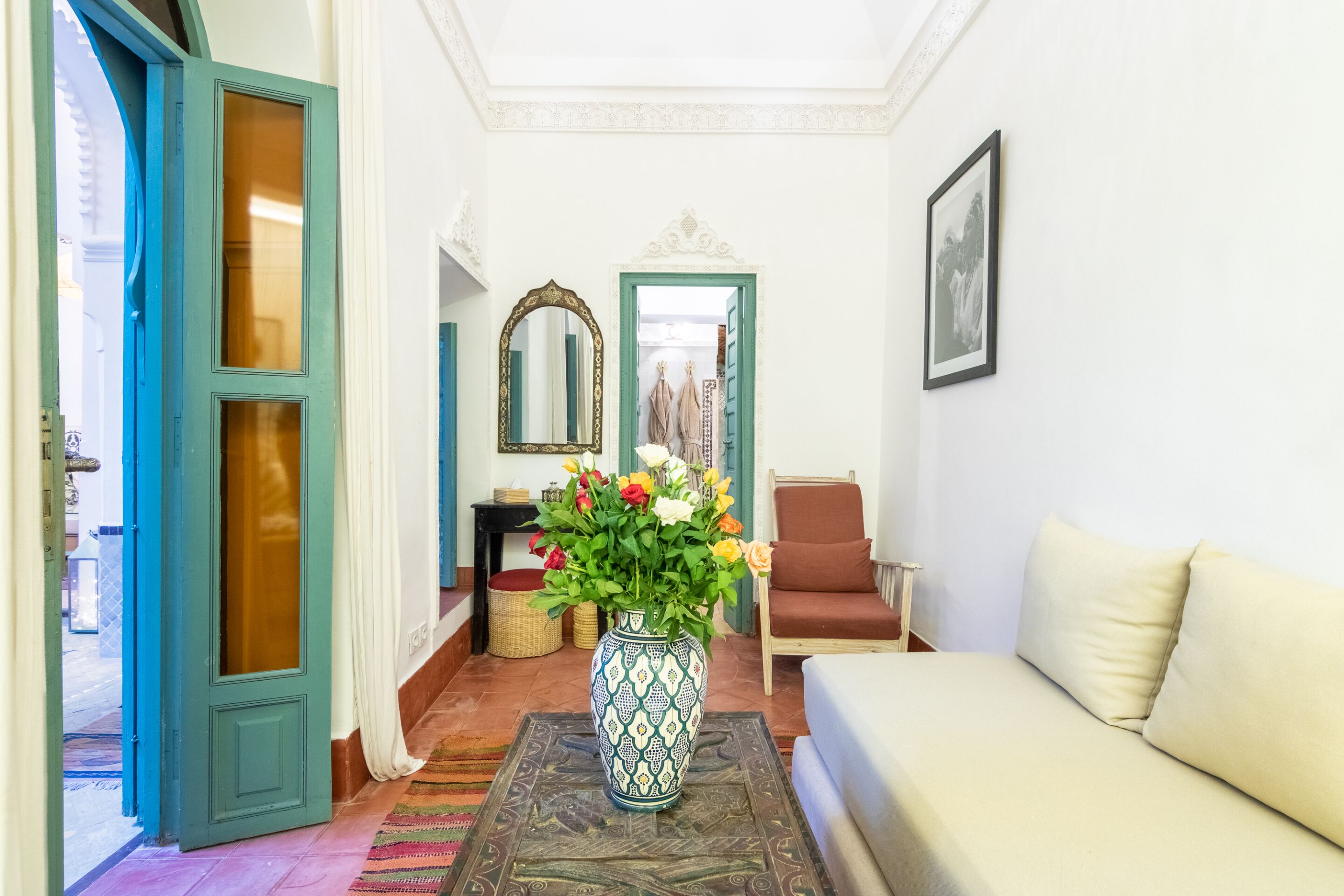 A room with a sofa, a coffee table with a vase, a chair, and a door with glass panels.