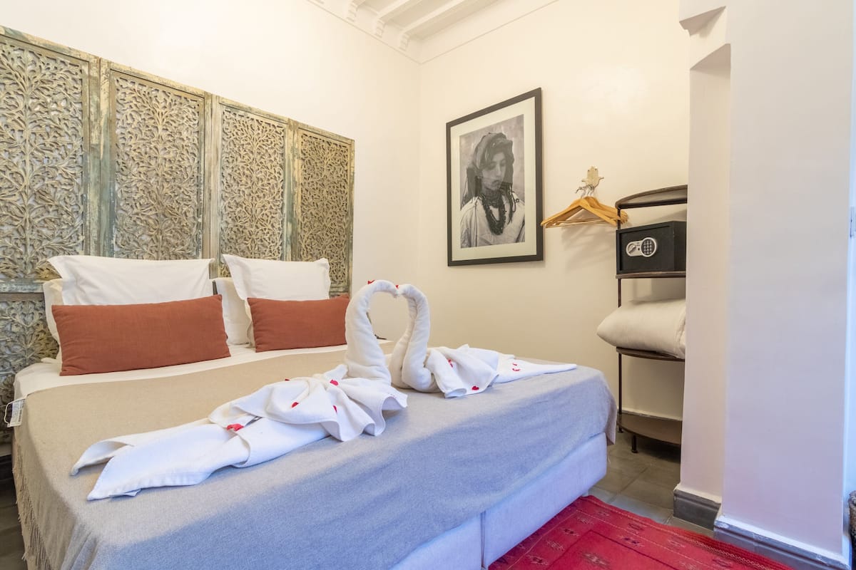 Een hotelkamer met een opgemaakt bed, een ingelijste afbeelding aan de muur en een decoratief paneel.