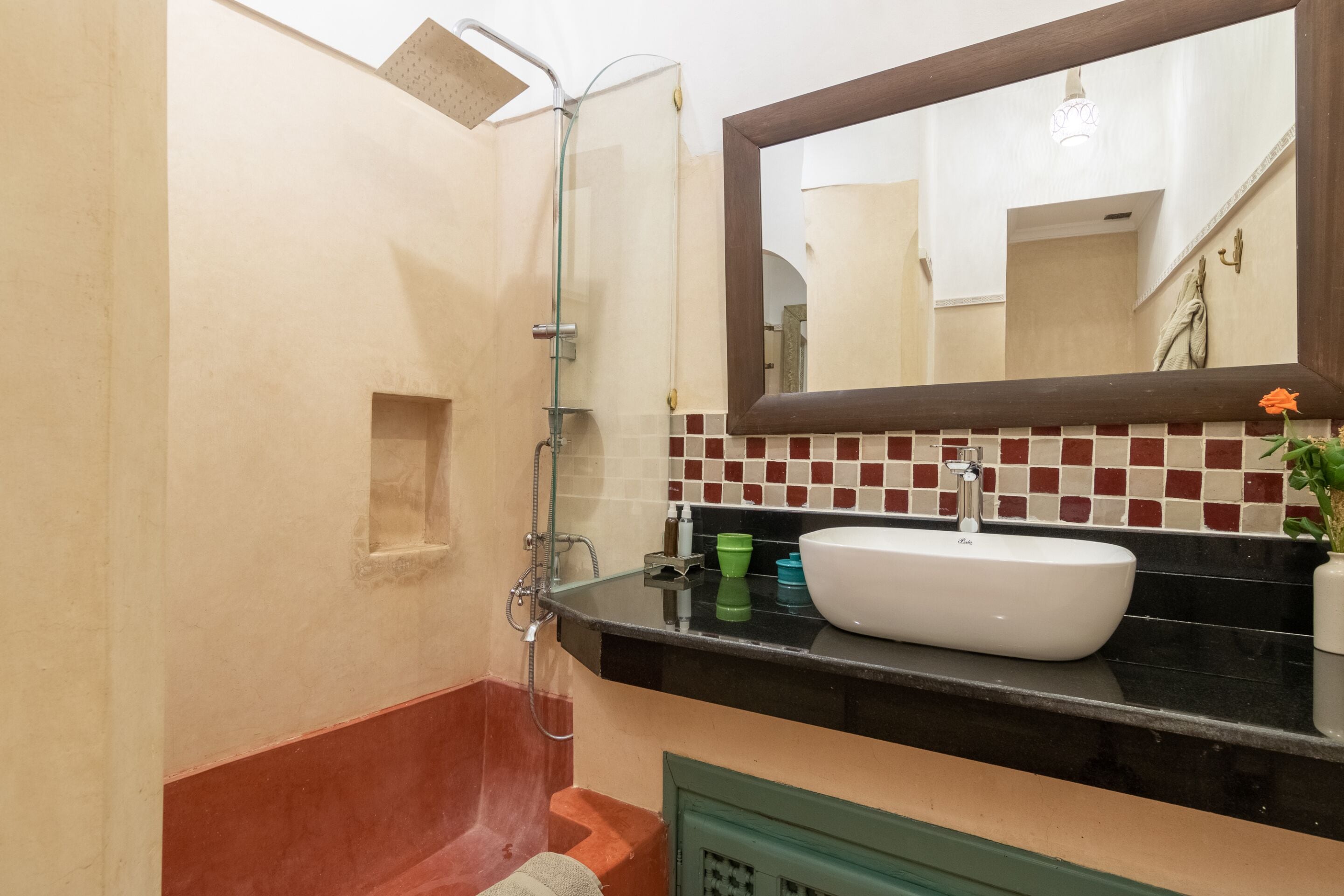 A bathroom with a shower, sink, mirror, and tiled backsplash.