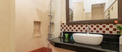 A bathroom with a shower, sink, mirror, and tiled backsplash.
