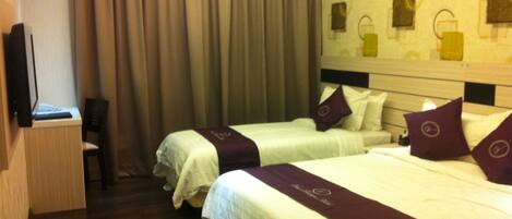 A hotel room with two beds, a desk, and a TV.