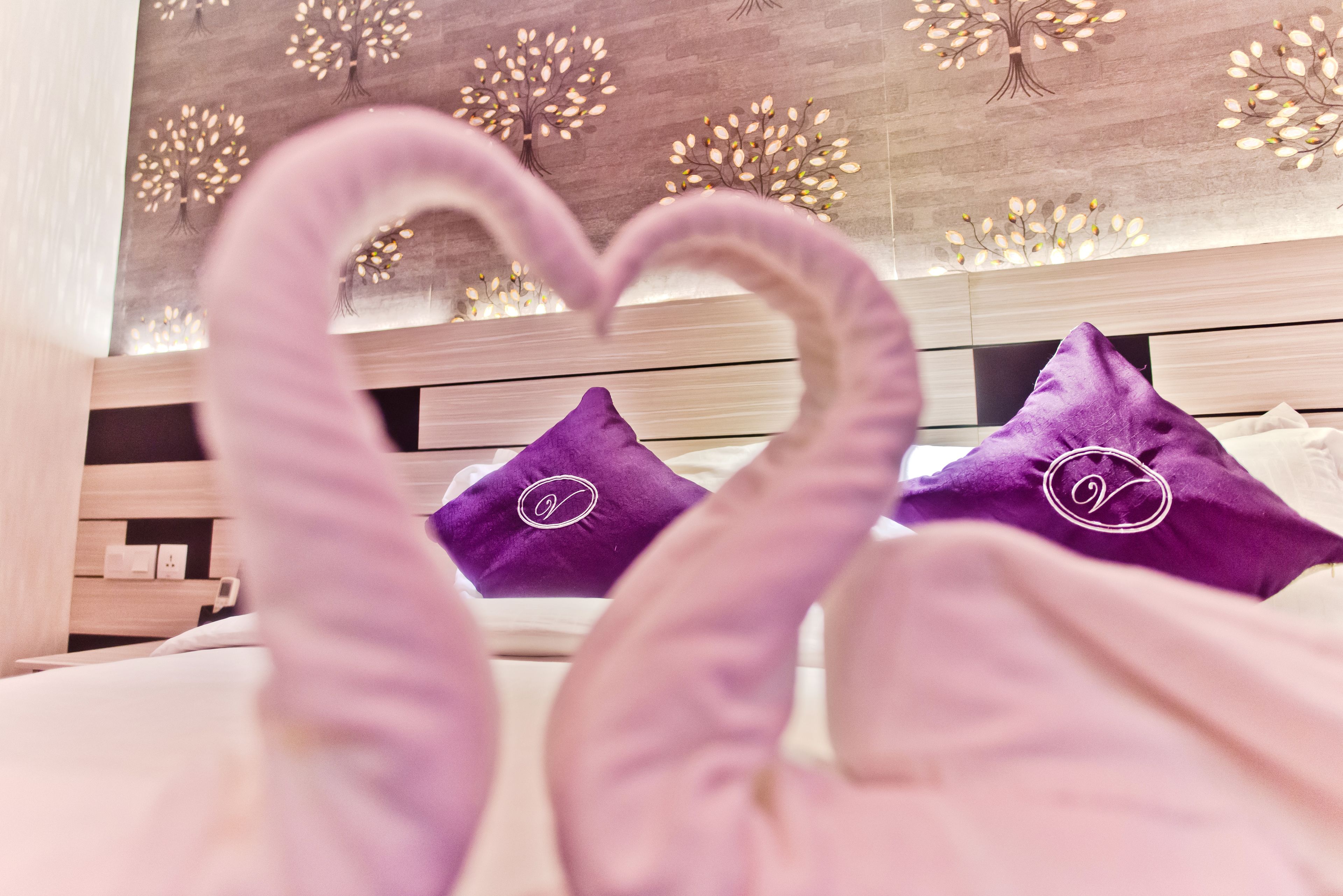 Un letto con cuscini viola e una decorazione a forma di cuore realizzata in tessuto.