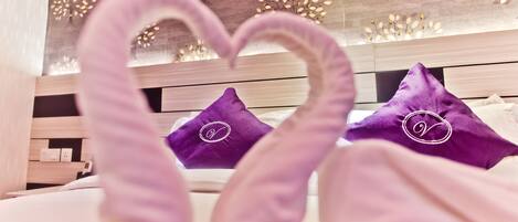 Un letto con cuscini viola e una decorazione a forma di cuore realizzata in tessuto.