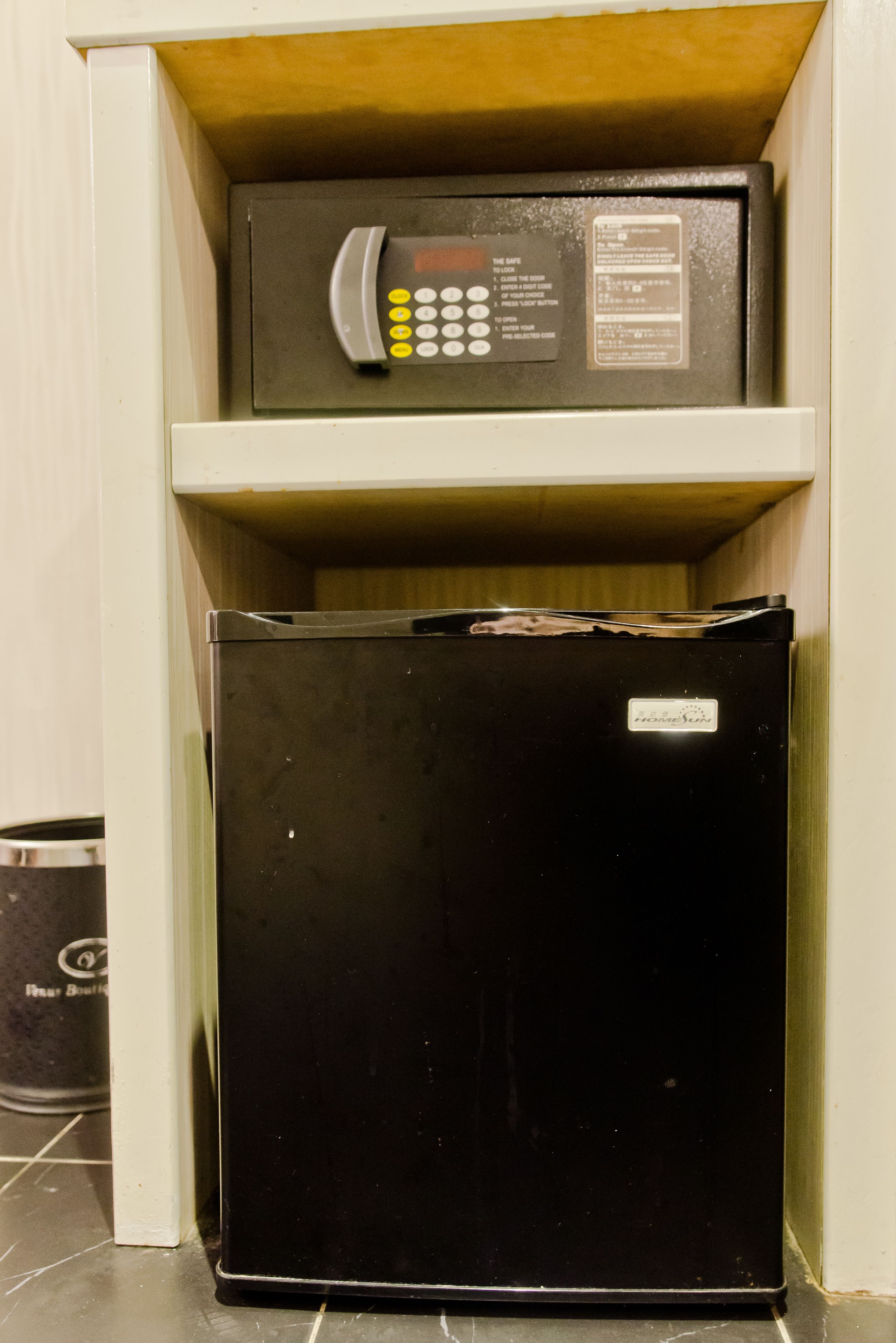 A black refrigerator and a microwave on a shelf in a kitchen.