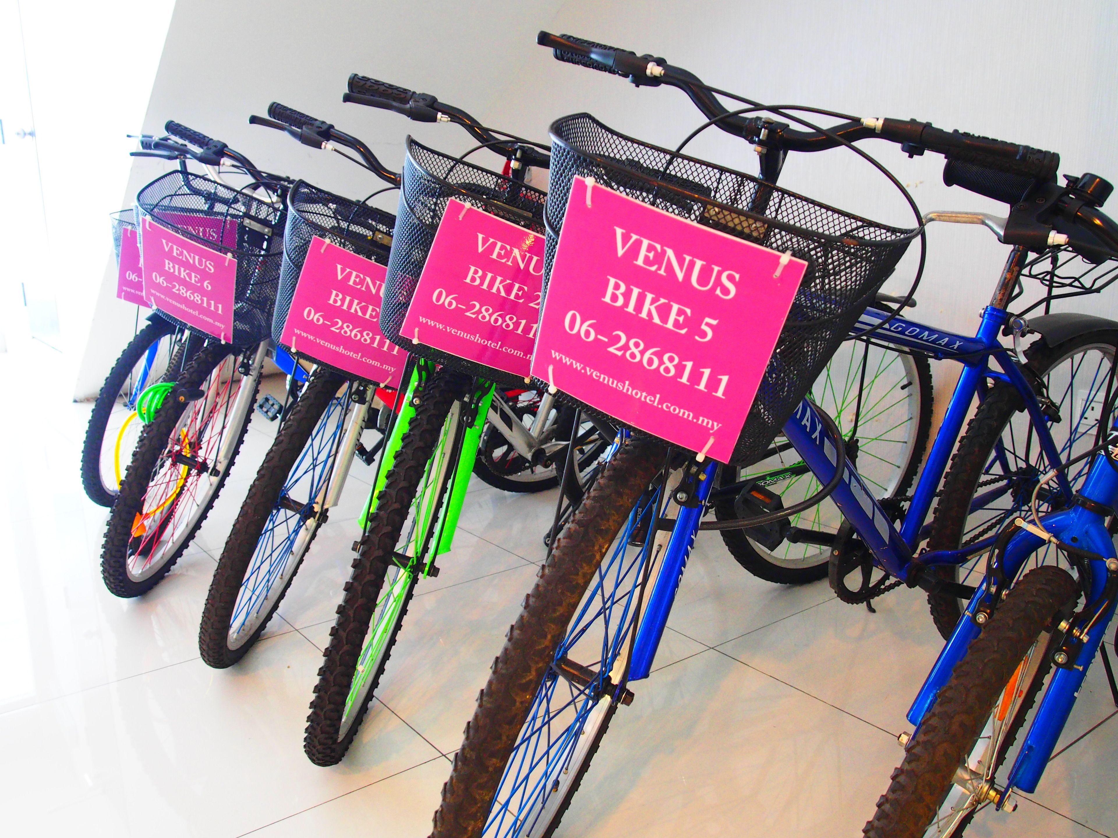 Una fila de bicicletas con letreros rosas que señalan disponibilidad para alquiler.