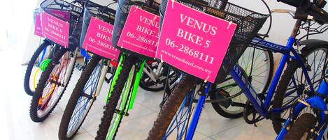 Una fila de bicicletas con letreros rosas que señalan disponibilidad para alquiler.