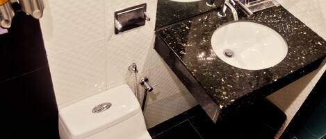 Une salle de bain équipée de toilettes, d’un lavabo et d’un sèche-cheveux fixé au mur.