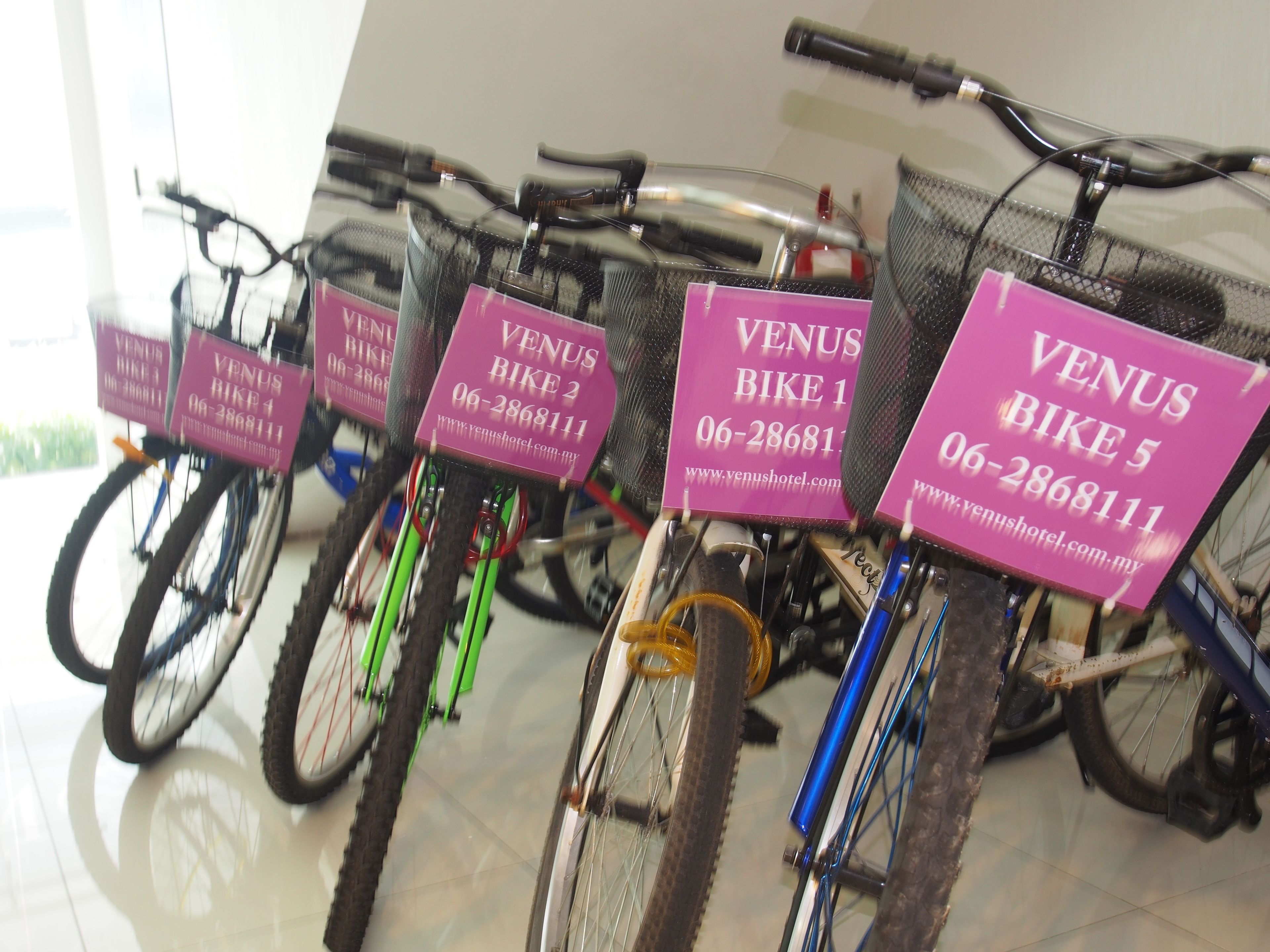 Une rangée de vélos, chacun portant un panneau rose indiquant les différentes options de location.