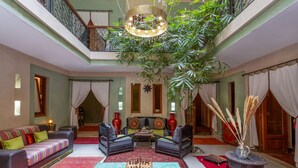 Un salón amplio con una mesa de ajedrez grande, asientos cómodos y un balcón con plantas.