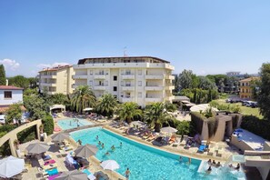 Ein Hotel mit Schwimmbad, mehreren Balkonen und einem angelegten Garten.
