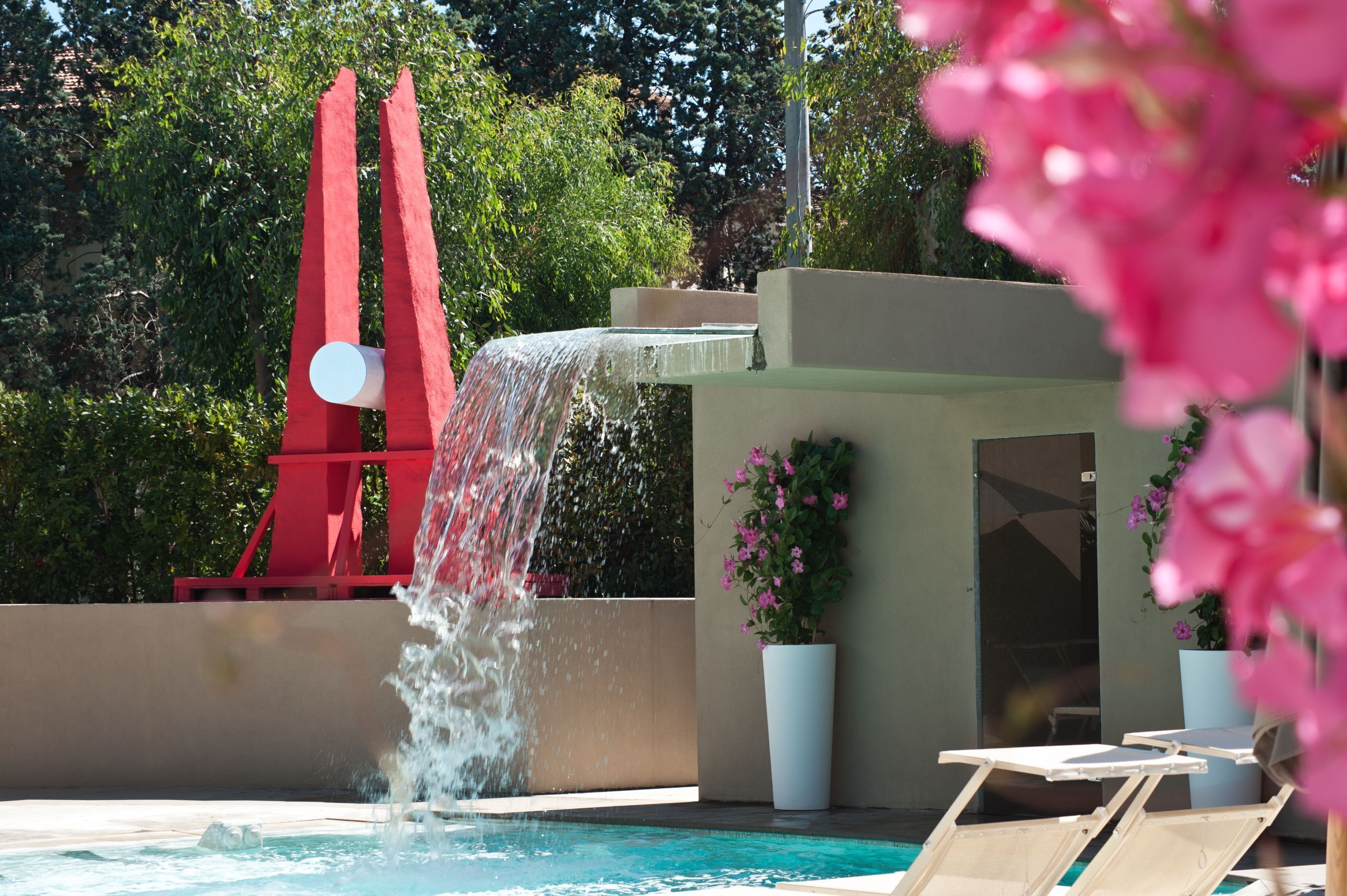 A pool with a water feature, red structures, and potted plants.