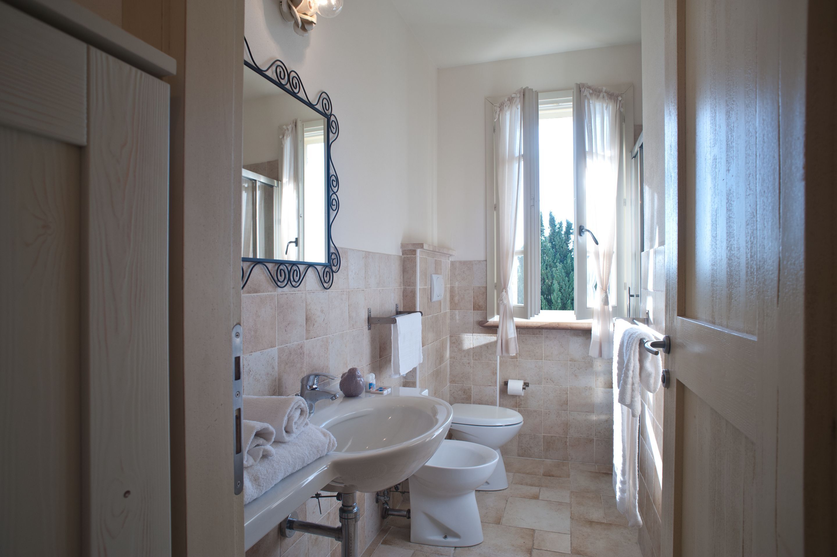 A bathroom with a sink, mirror, and two toilets.