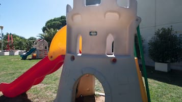 Kids can play and explore a castle-themed play structure with a slide and tunnel entrance.