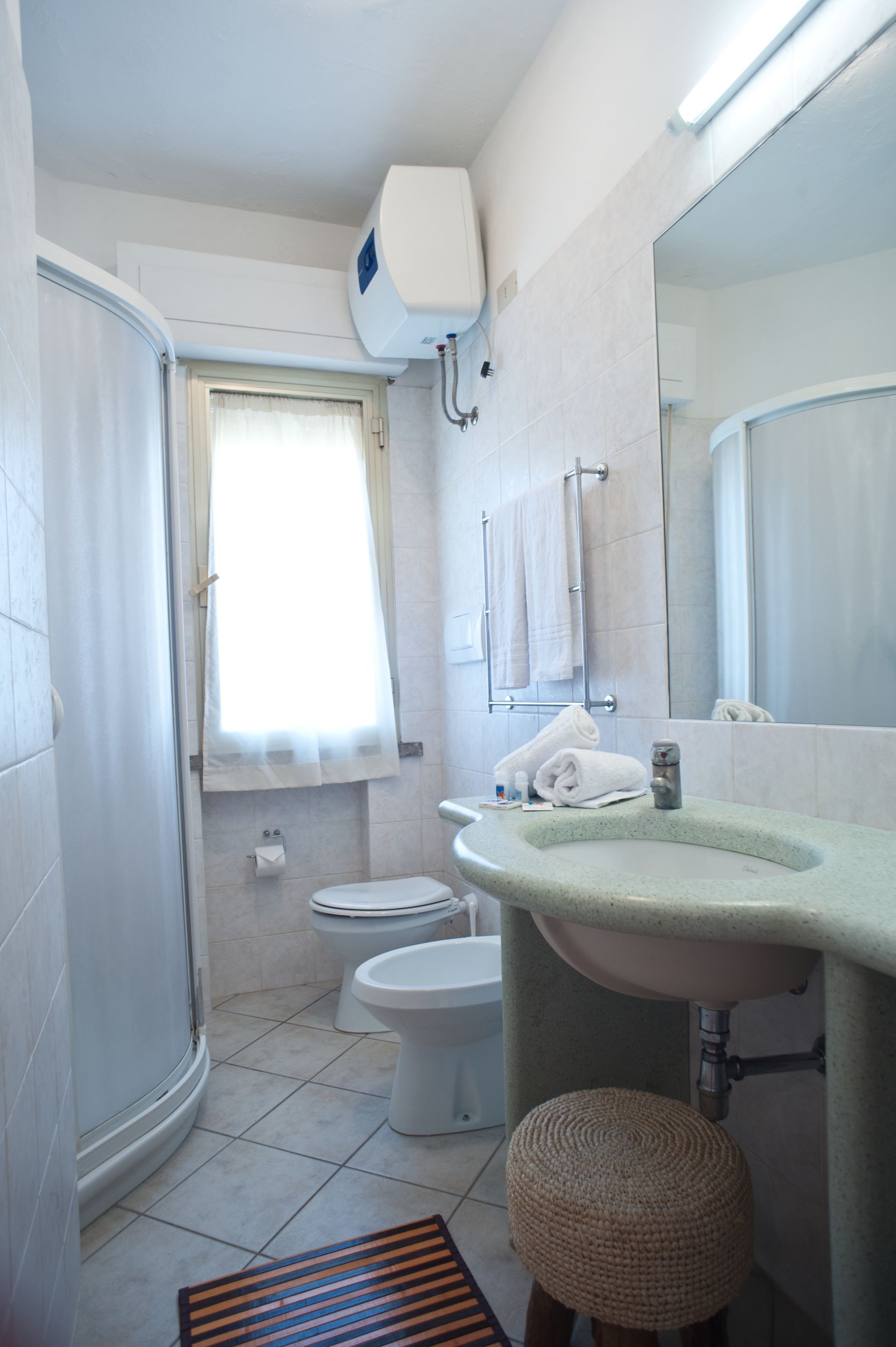 Une salle de bain équipée d’une douche, de toilettes, d’un lavabo et d’un miroir.