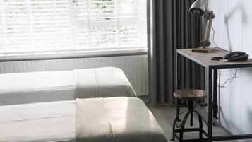 A room with two beds, a desk with a lamp, and a chair.