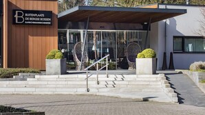 Un edificio moderno con fachada de madera y un letrero que dice "Buitenplaats De Bergse Bossen".