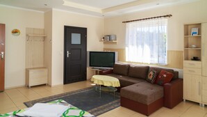 A living room with a sofa, a television, a small table, and a cabinet. - Willa Mewa (Gdynia)