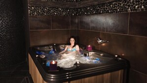 A woman in a hot tub with a stone wall and a candle. - Hotel 77 Restauracja Spa (Wladyslawowo)