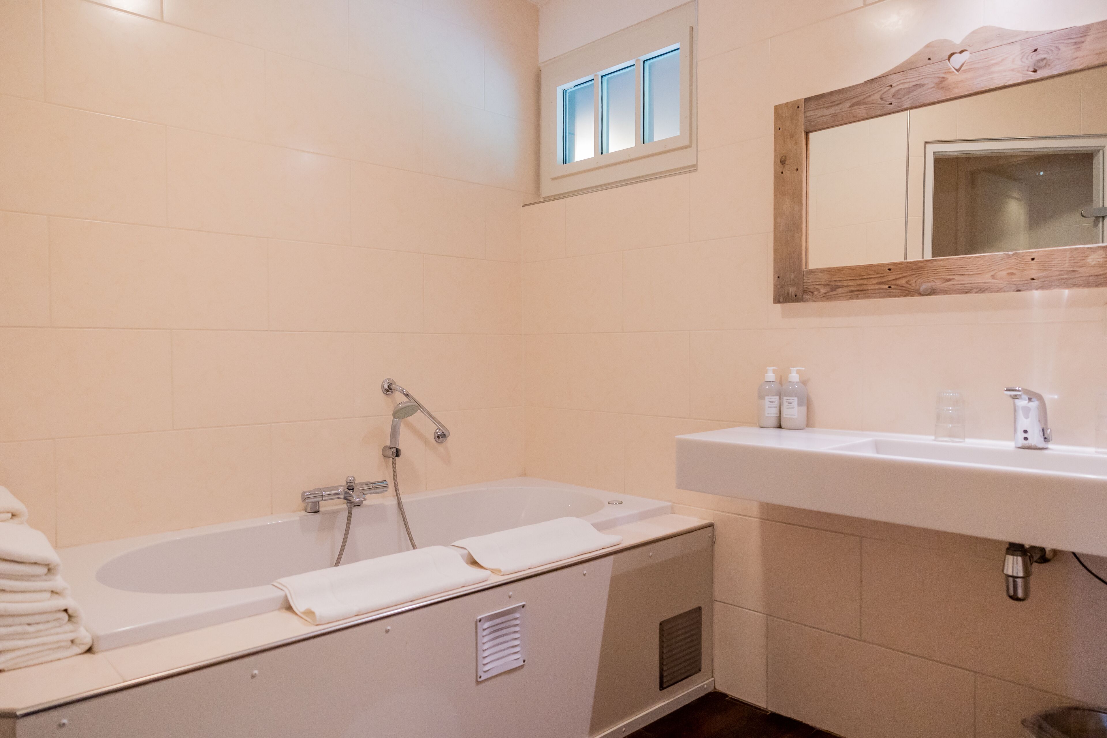 Een badkamer met een bad, een wastafel en een spiegel.