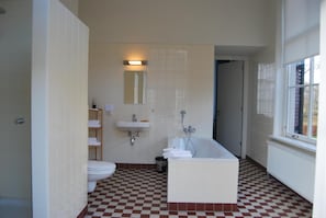 A bathroom with a checkered floor, a white bathtub, a sink, and a toilet. - Bitter en Zoet (Veenhuizen)
