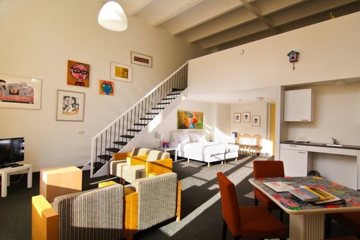 Un salon moderne avec un escalier, un coin repas et une cuisine.