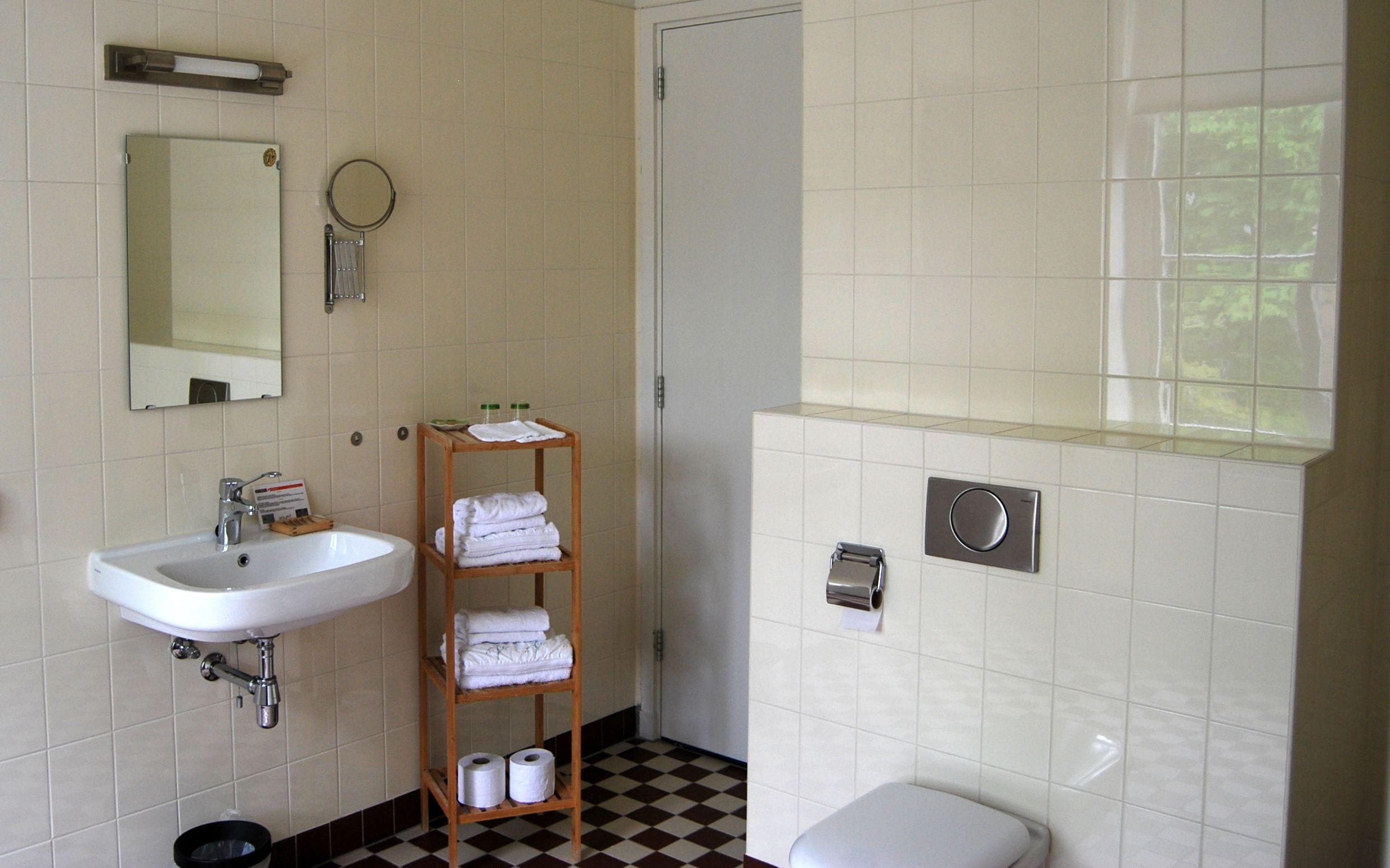 Een badkamer met een wit wastafel, spiegel, handdoekhouder en toilet.