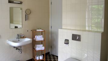 Een badkamer met een wit wastafel, spiegel, handdoekhouder en toilet.