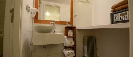 A bathroom with a white sink, a mirror, a towel rack, and a heater.