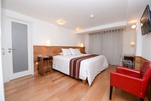 Een hotelkamer met een bed, nachtkastjes, een bureau, een stoel en een aan de muur bevestigde televisie.