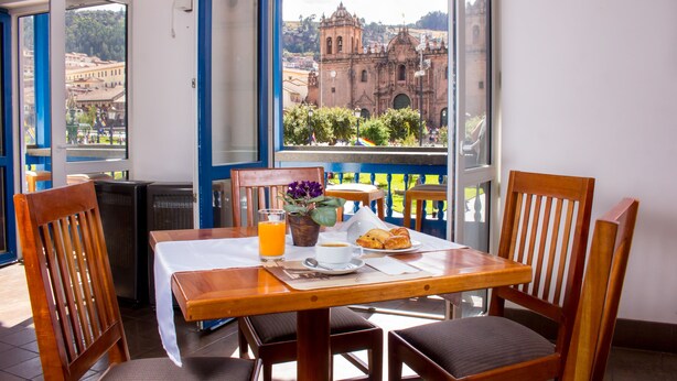 Ein Balkon mit Frühstückstisch, Blick auf ein historisches Gebäude und einem Blumentopf.