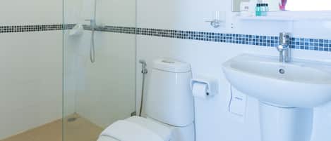 Un baño moderno con ducha de vidrio, inodoro blanco y lavabo con espejo.