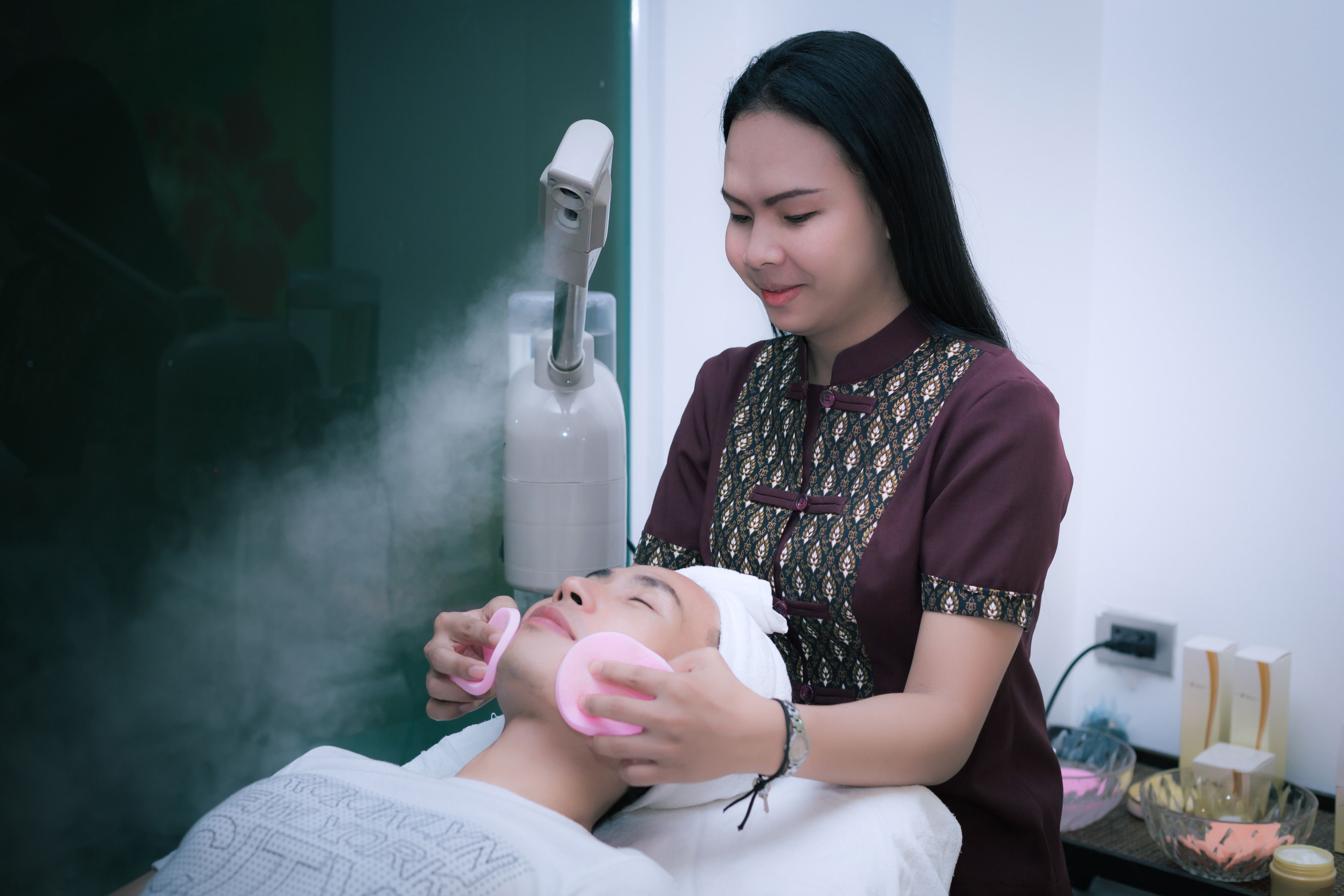 Una persona recibiendo un tratamiento facial con vapor y una mascarilla.