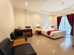 A hotel room with a bed, a desk, a chair, a small table, and a sofa. - Zing Resort & Spa (Pattaya)