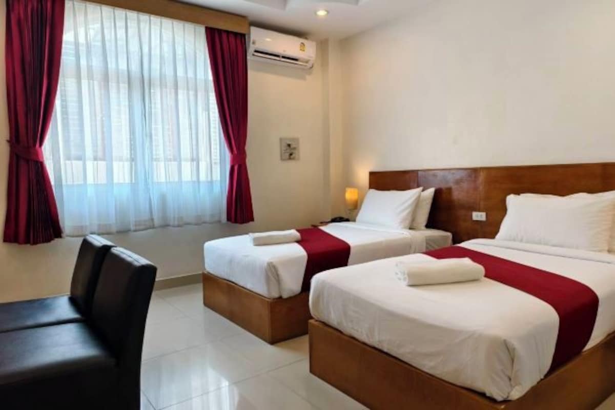A hotel room with two beds, a desk, and a chair.