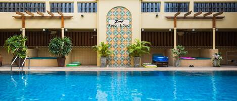 A swimming pool with a tiled wall featuring a sign for 'Zing Resort & Spa'.