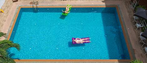 Una piscina rectangular con dos sillas de descanso y una pequeña terraza.