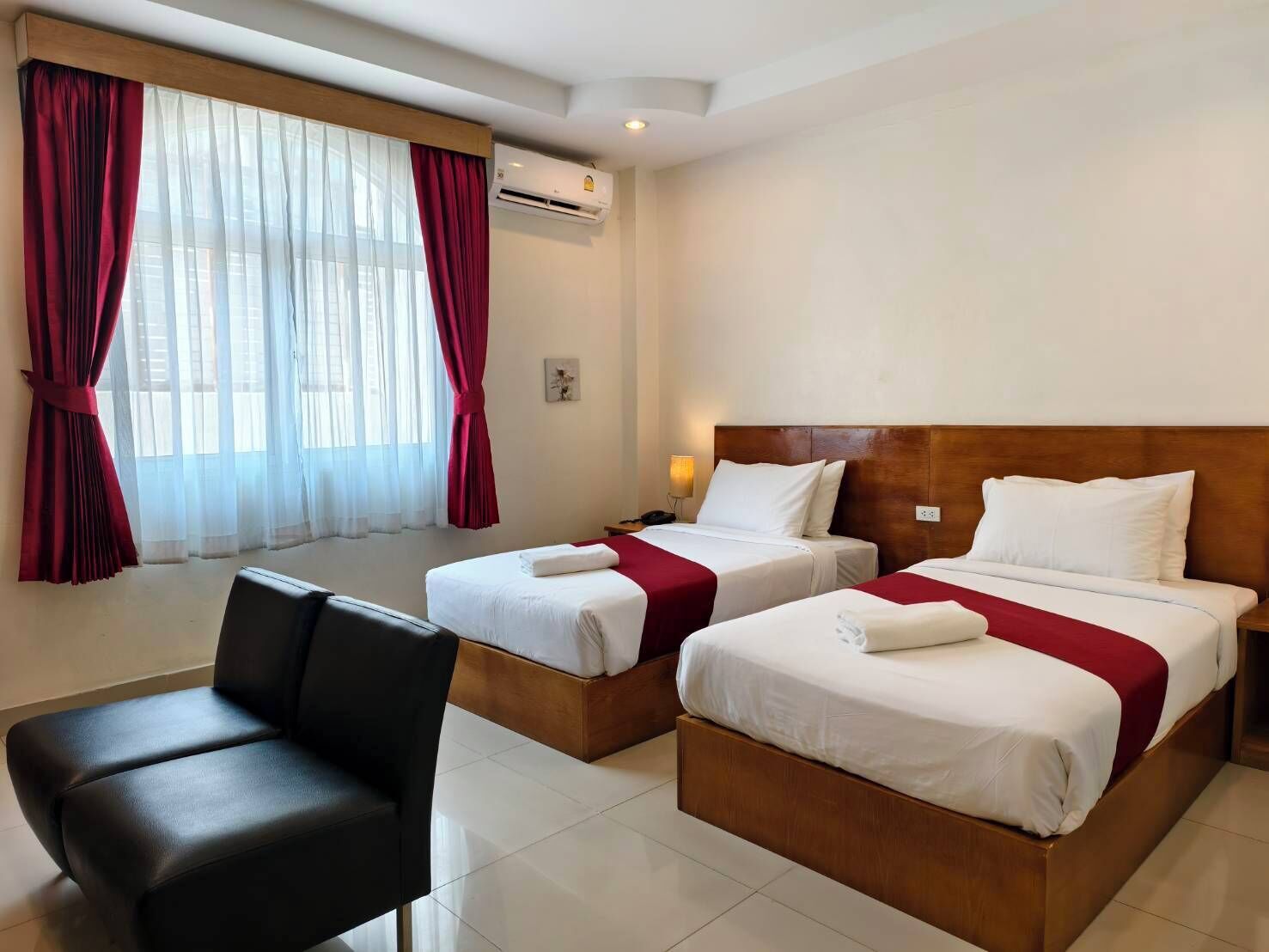 Une chambre d’hôtel avec deux lits, un bureau, une chaise et une fenêtre avec des rideaux.