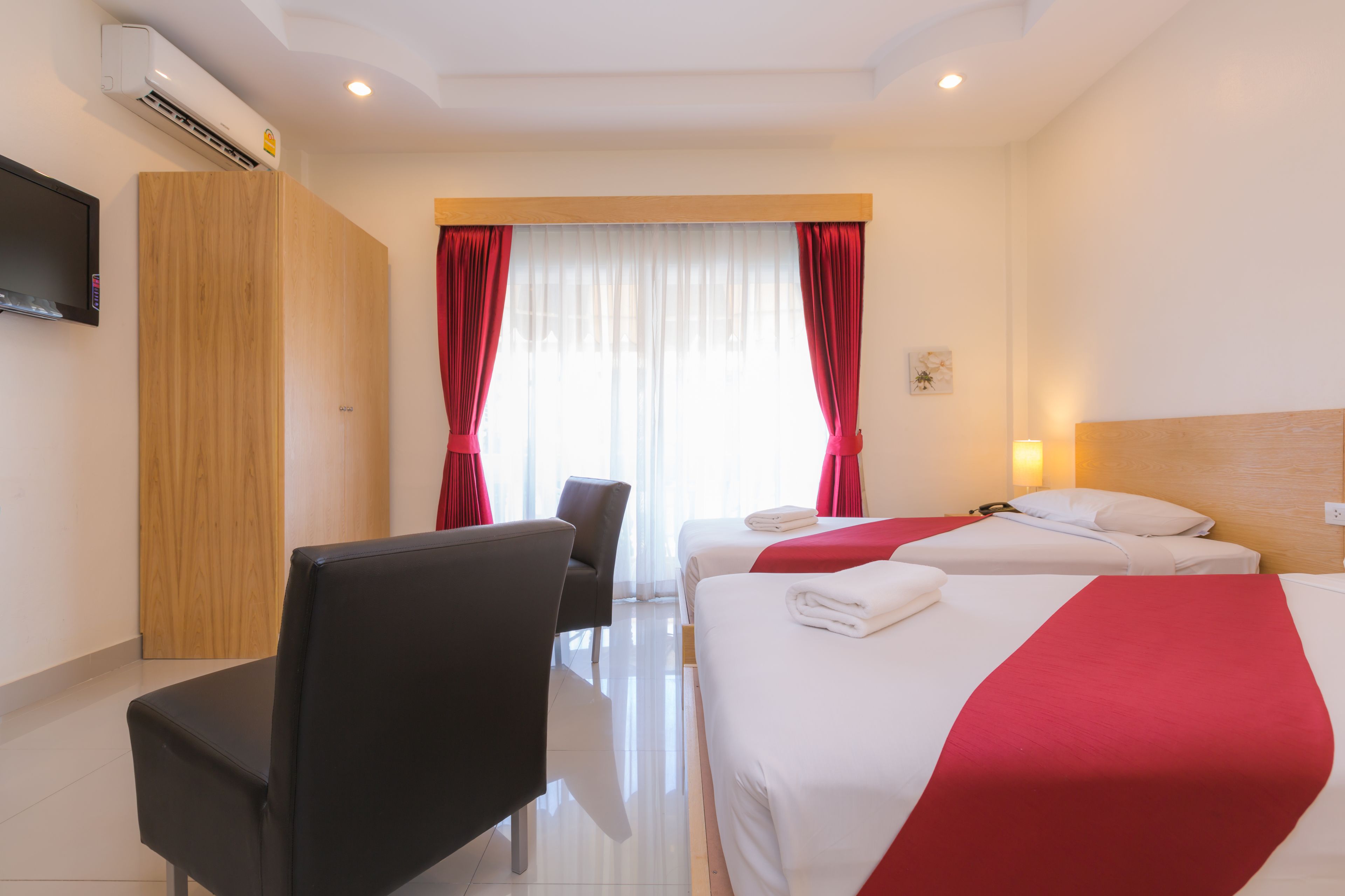 Een hotelkamer met twee bedden, een televisie, een bureau en een stoel.