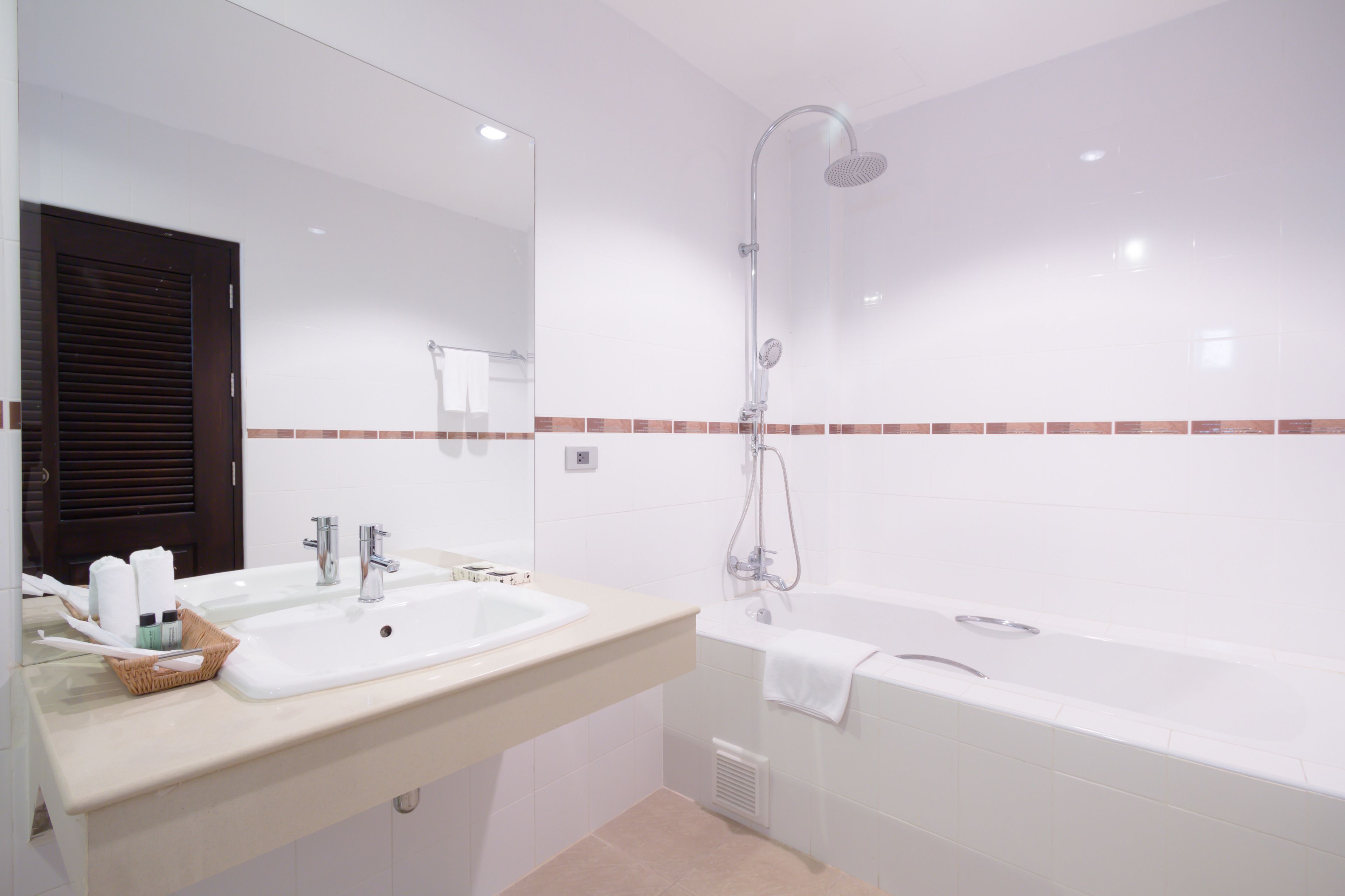 A modern bathroom with a double sink, a bathtub, and a large mirror.
