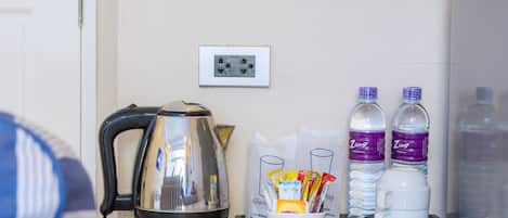 A kitchen counter with a kettle, water bottles, and a coffee maker.