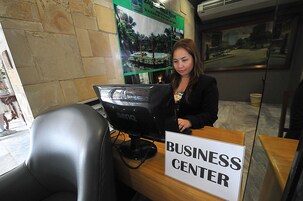 A business center with a computer monitor, a sign reading "BUSINESS CENTER", and a poster on the wall.
