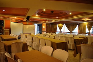 A conference room with rows of tables and chairs, a whiteboard, and a projector screen.