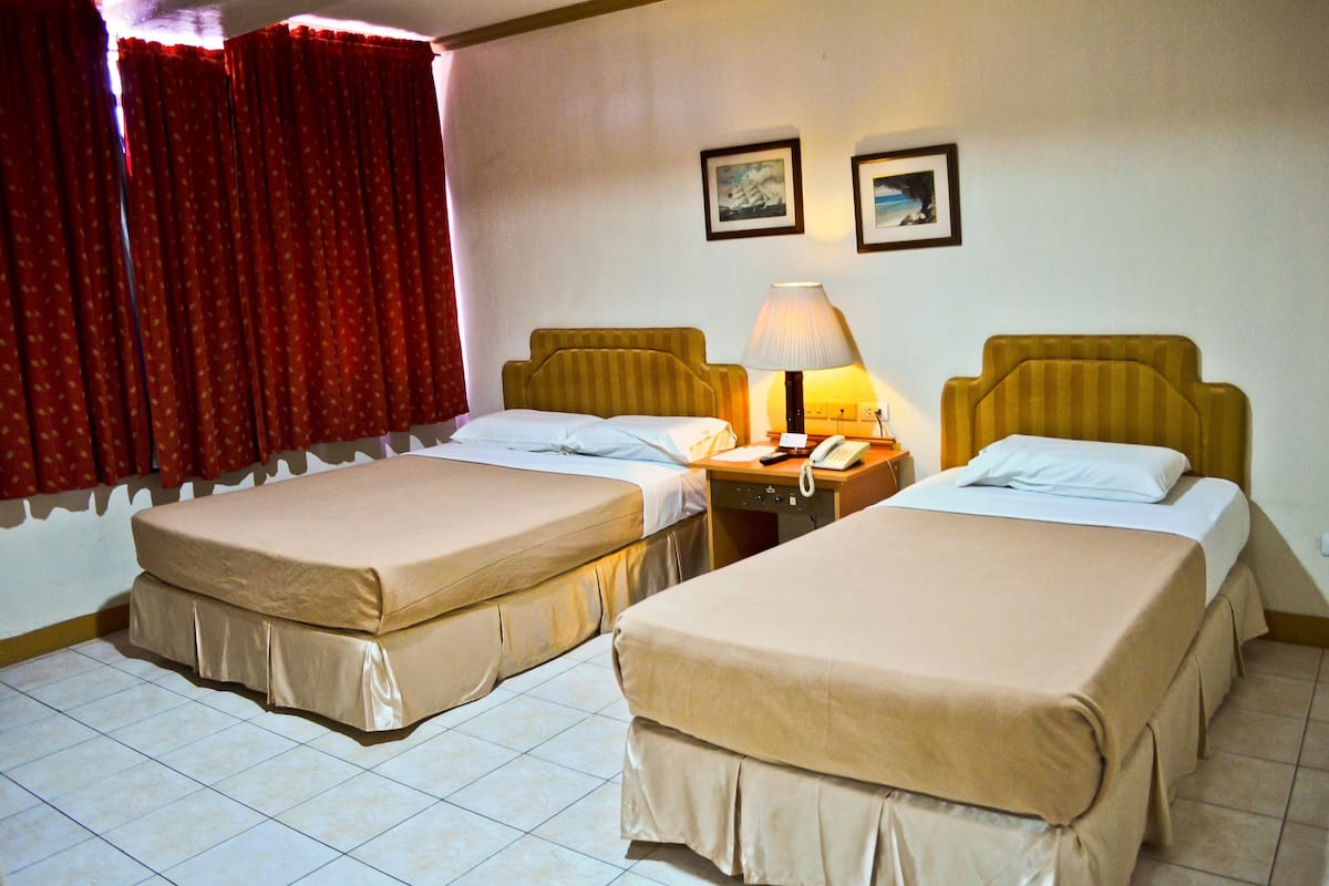 A hotel room with two single beds, a nightstand with a lamp, and a telephone.