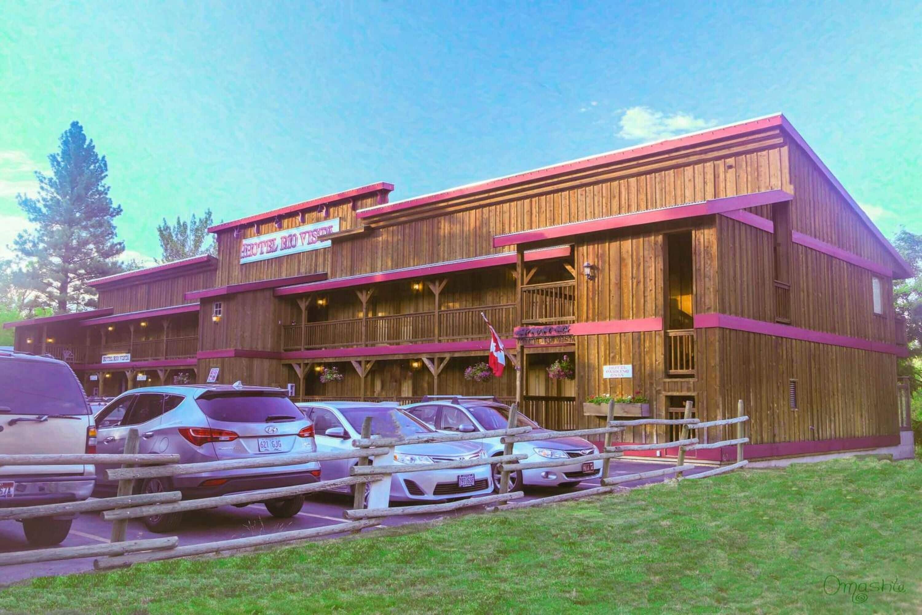 A wooden building with a sign reading "Hotel Rio Vista." There are cars parked in front.