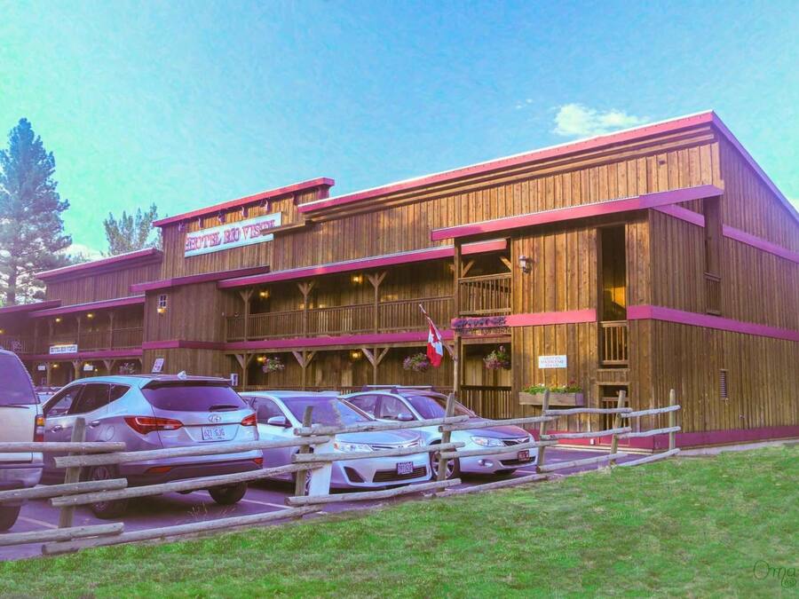 A wooden building with a sign reading "Hotel Rio Vista." There are cars parked in front.