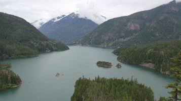 A lake surrounded by forested mountains with a cloudy sky.