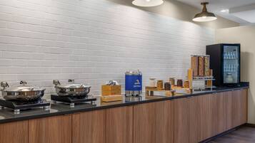 A breakfast bar with a variety of food items and a coffee machine.