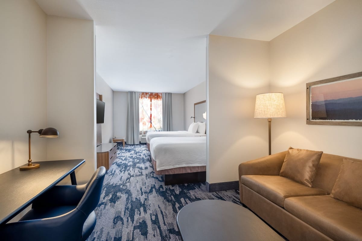Une chambre d’hôtel avec un lit, un bureau, une chaise, un canapé, une lampe et un tableau au mur.