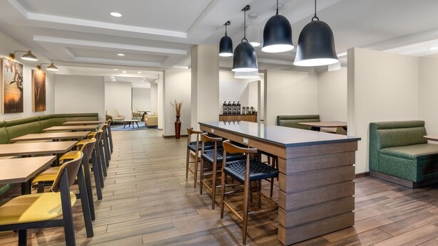 A modern restaurant with wooden flooring, green cushioned seating, and pendant lighting. - Fairfield Inn & Suites by Marriott Fort Walton Beach Hurlburt Area (Fort Walton Beach)