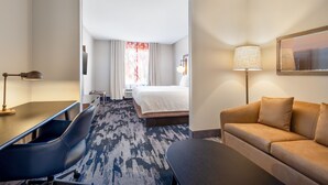 A hotel room with a bed, a desk, a sofa, a lamp, and a painting on the wall. - Fairfield Inn & Suites by Marriott Fort Walton Beach Hurlburt Area (Fort Walton Beach)